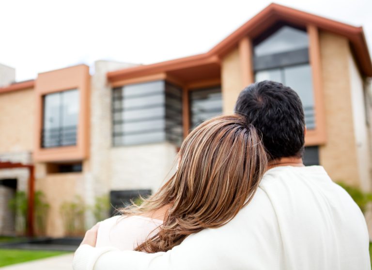 Couple embracing while looking at a modern house